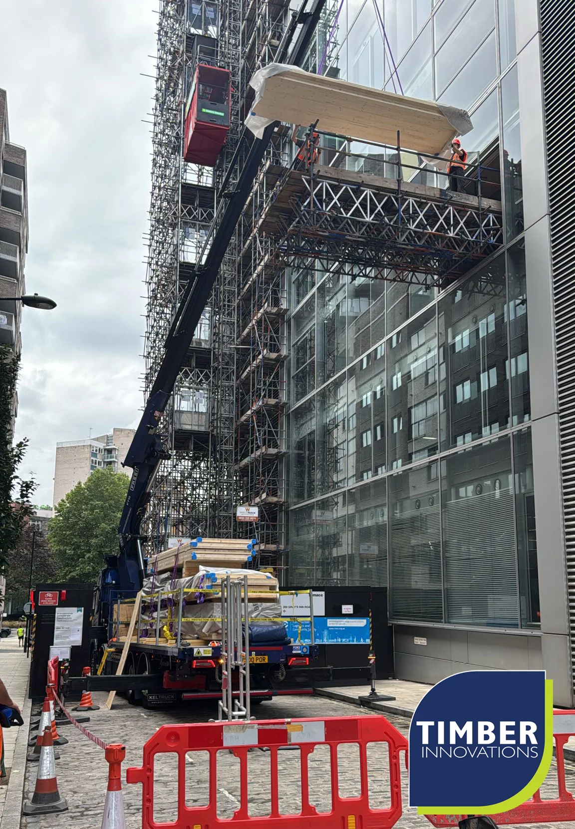 521269935_1173168404832527_6716136053134214670_n Crane lifting panels next to glass building
