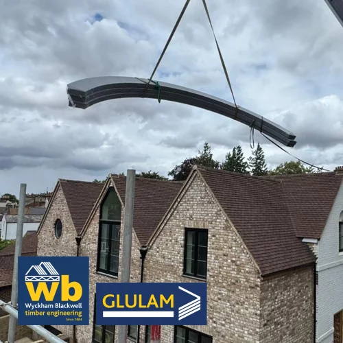 Glulam beams being lifted on crane over houses