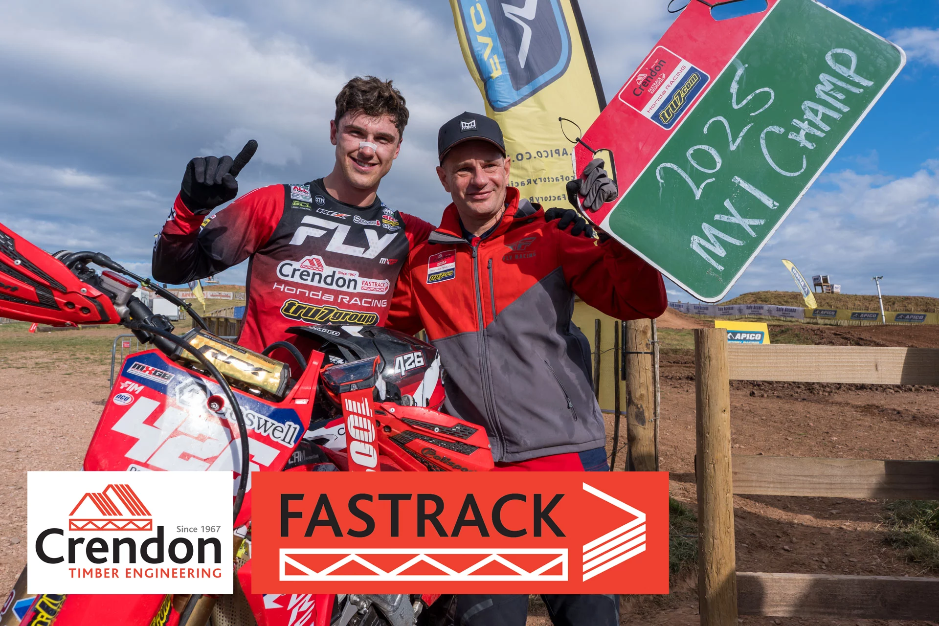Two men posing for winning photo next to MX bike