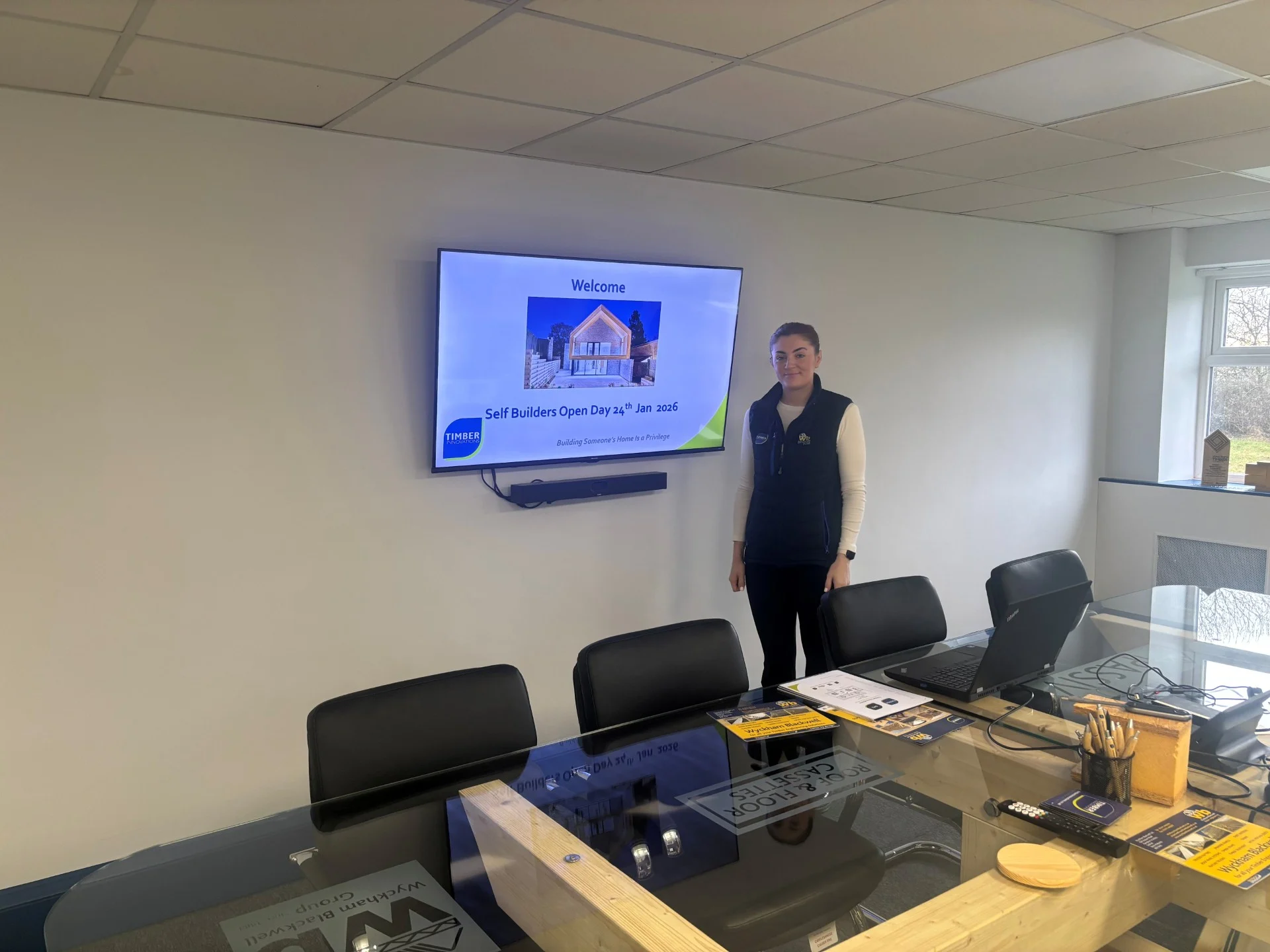 A lady standing in front of a screen with the Self Build Workshop details on a TV screen. A lady standing in front of a screen with the Self Build Workshop details on a TV screen.