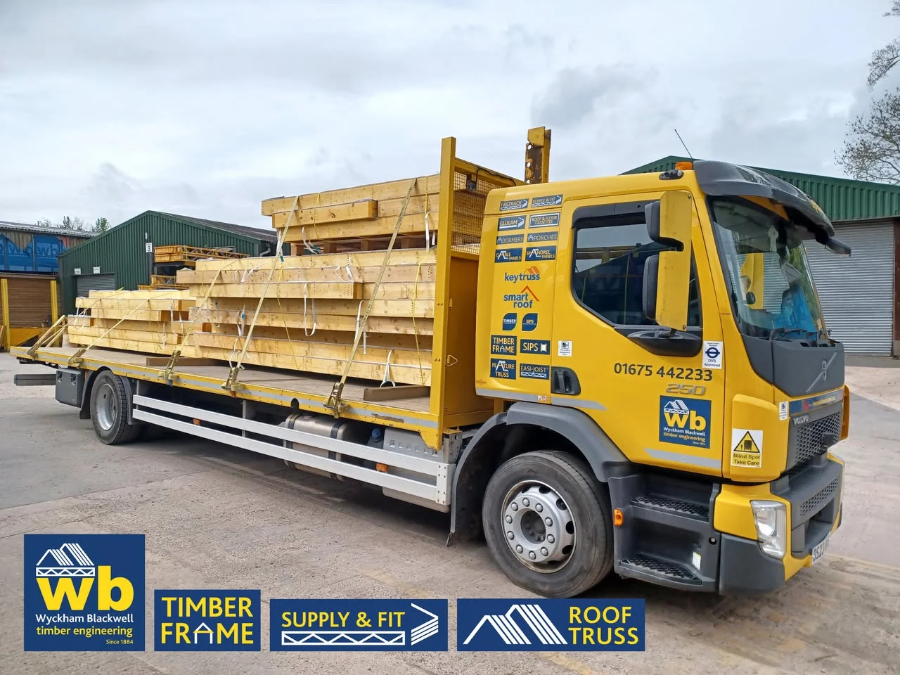 Yellow Wyckham Blackwell lorry with piles of timber on the back
